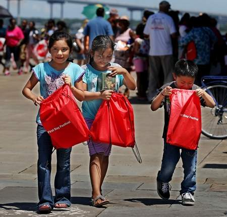 Three Children Carrying Bags of Supplies