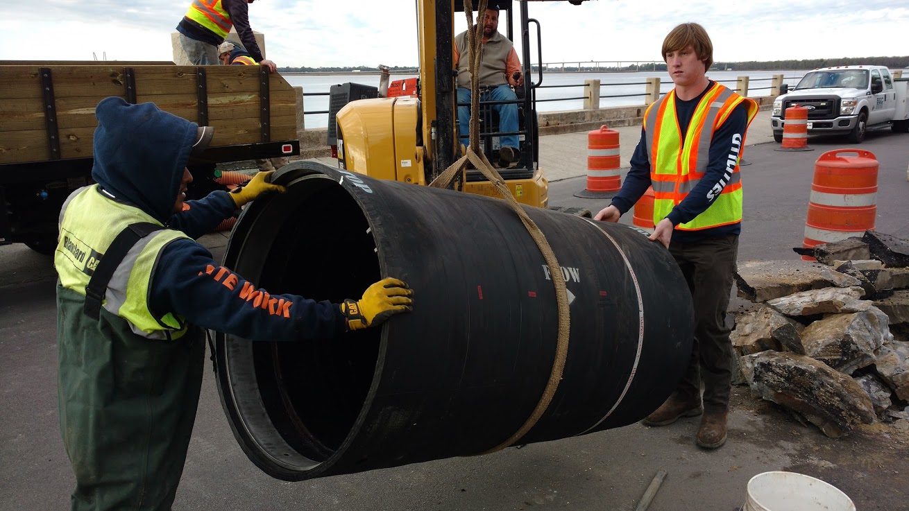Men preparing large pipe to be laid into the ground